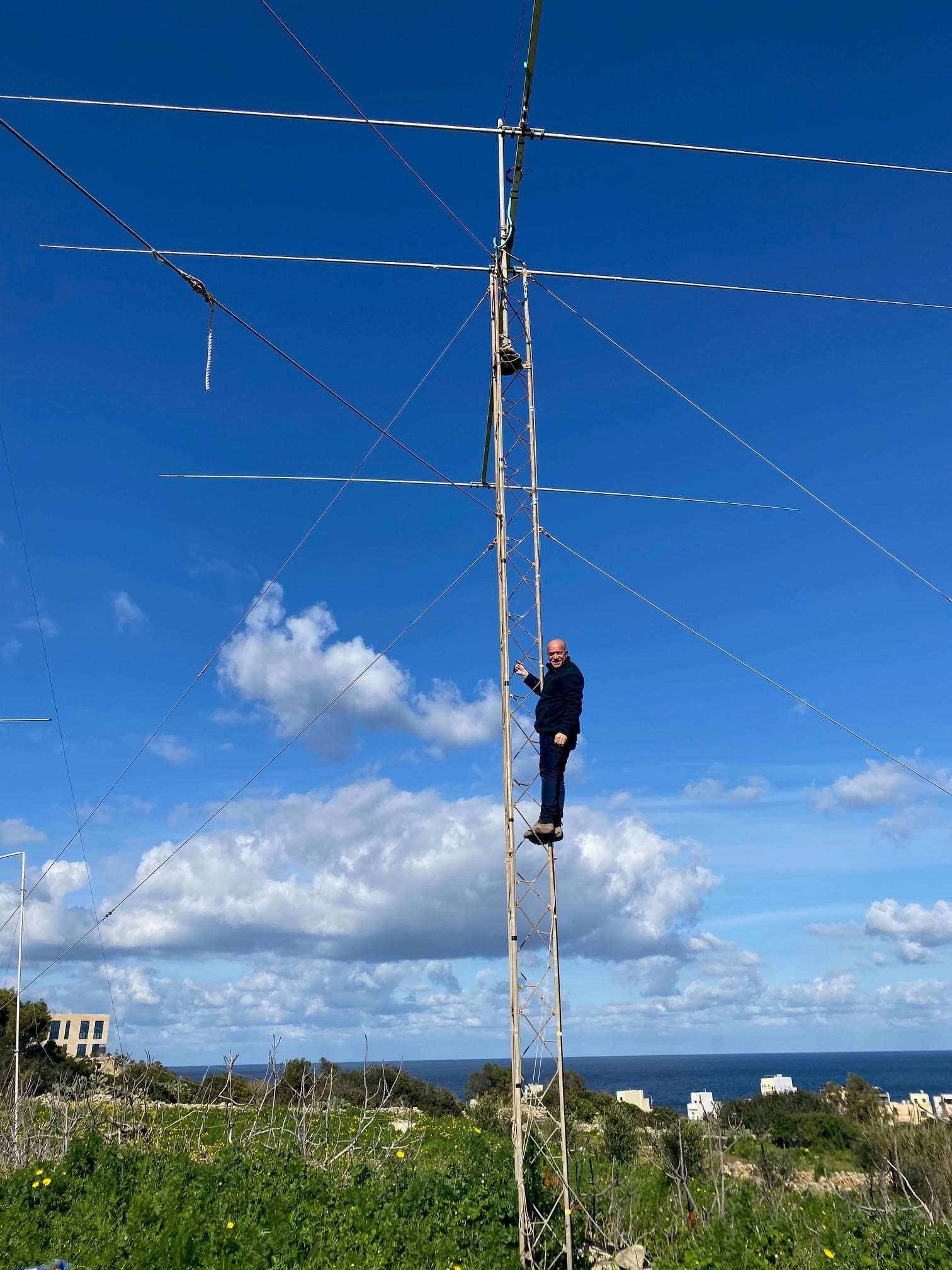 Amir beside a tower and antenna system in Malta