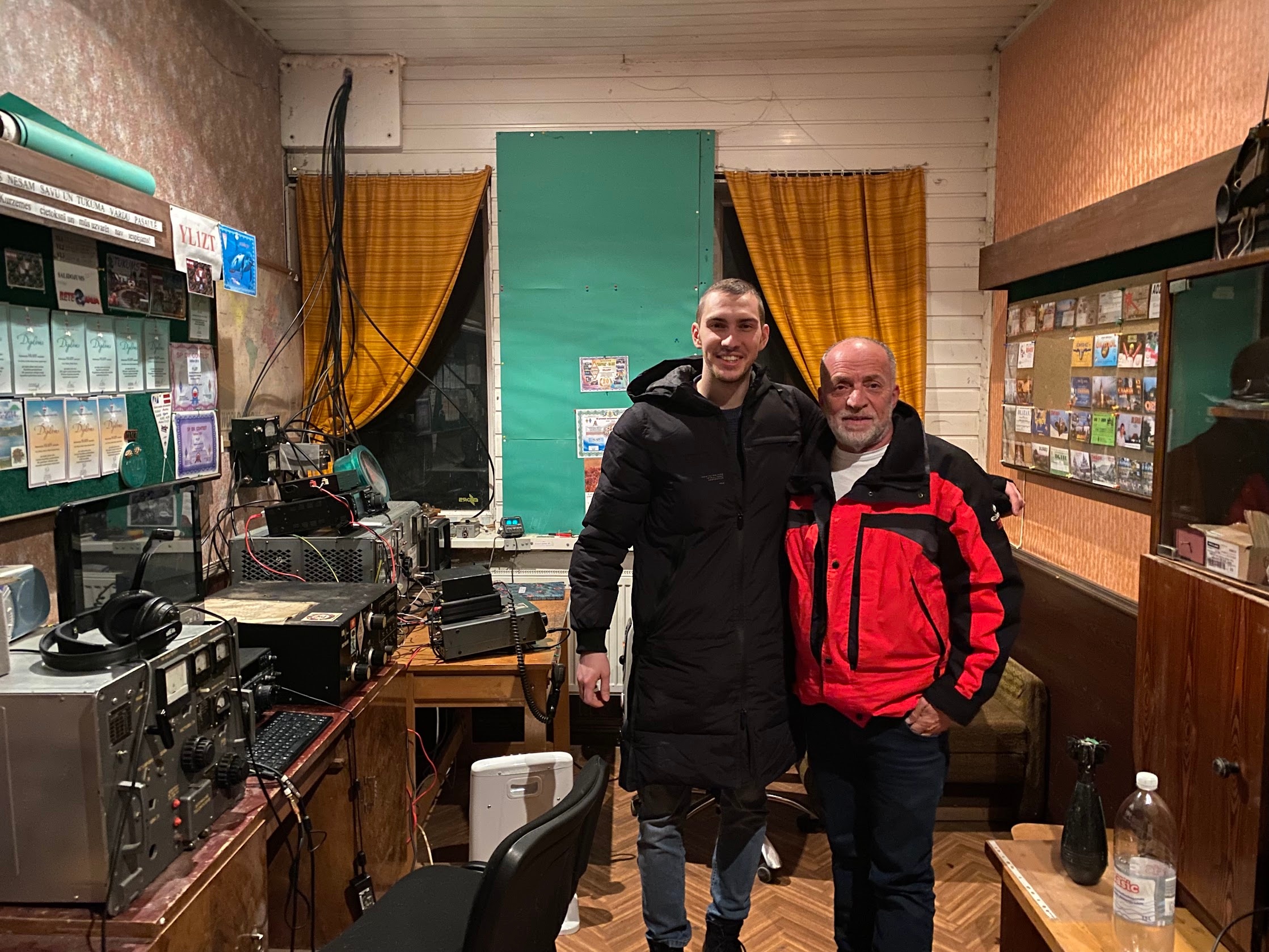 Two radio friends beside amateur-radio equipment and QSL cards in Tukums, Latvia, on 15 February 2023.